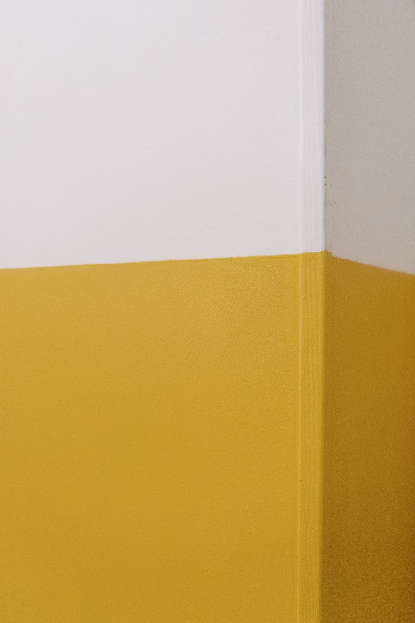 Mur peint en deux tons, blanc en haut et jaune en bas, séparés par une ligne parfaitement droite.
